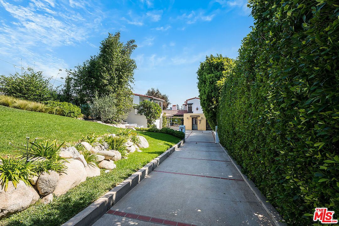 Two-story Spanish Colonial wing of 1046 Chautauqua. White stucco facade, red clay tile roof, attached garage, surrounded by mature greenery.